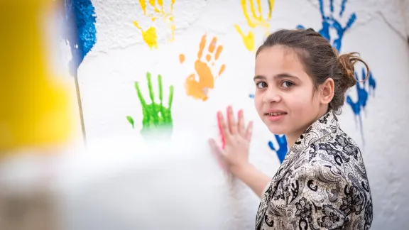 A young Jordanian girl painting the wall with her hands