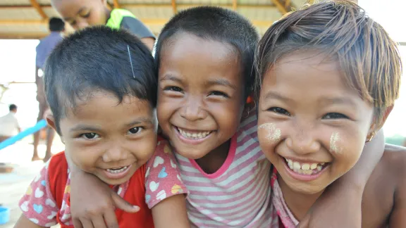Three kids from Myanmar smiling at the camera