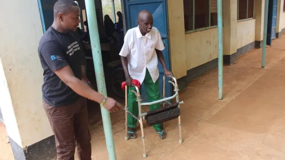 Supported by his special education teacher, Sankus makes gradual walking progress out of his classroom at Hormuud Primary School in Ifo refuge camp of Dadaab.